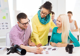 Image showing smiling team with printed photos working in office