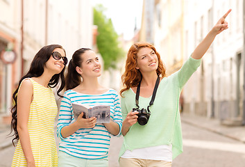 Image showing smiling teenage girls with city guide and camera