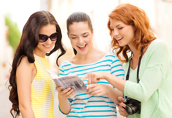 Image showing smiling teenage girls with city guide and camera