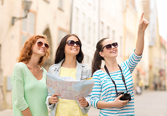 Image showing smiling teenage girls with map and camera