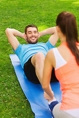 Image showing smiling man doing exercises on mat outdoors