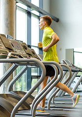 Image showing smiling man exercising on treadmill in gym