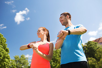 Image showing smiling people with heart rate watches outdoors