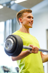 Image showing smiling man doing exercise with barbell in gym