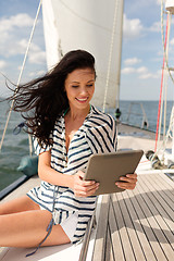 Image showing smiling woman sitting on yacht with tablet pc