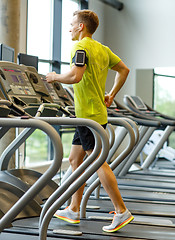 Image showing man with smartphone exercising on treadmill in gym