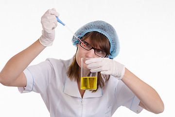 Image showing Chemist finds drops falling into a flask