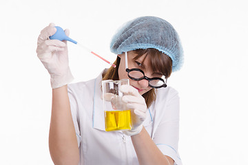 Image showing Laboratory assistant liquid drips from a pipette into flask