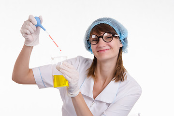 Image showing Chemist liquid drips into a flask