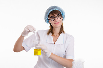 Image showing Chemist mixes the contents of flask