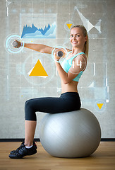 Image showing smiling woman with dumbbells and exercise ball