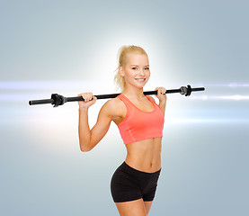 Image showing smiling sporty woman exercising with barbell