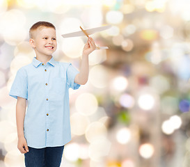 Image showing smiling little boy holding a wooden airplane model