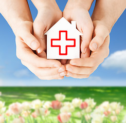 Image showing hands holding paper house with red cross