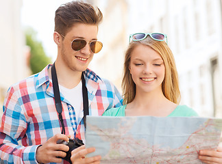 Image showing smiling couple with map and photo camera in city