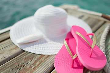 Image showing close up of hat, sunscreen and slippers at seaside