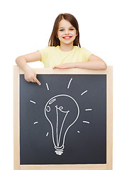 Image showing smiling little girl pointing finger to blackboard