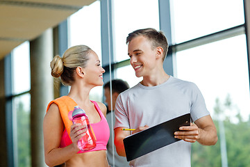 Image showing smiling young woman with personal trainer in gym