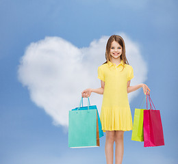 Image showing smiling little girl in dress with shopping bags