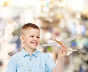 Image showing smiling little boy holding a wooden airplane model