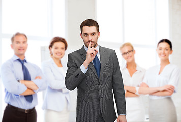 Image showing group of smiling businessmen making hush sign