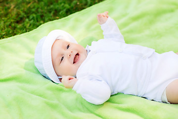 Image showing smiling baby lying on floor and looking up