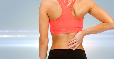 Image showing close up of sporty woman touching her back