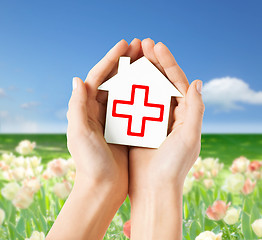 Image showing hands holding paper house with red cross