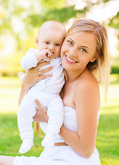 Image showing happy mother with little baby sitting on blanket