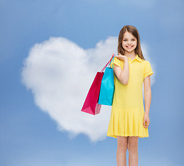 Image showing smiling little girl in dress with shopping bags