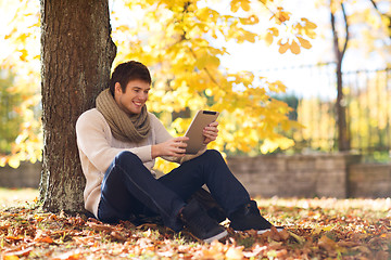 Image showing smiling young man with tablet pc in autumn park