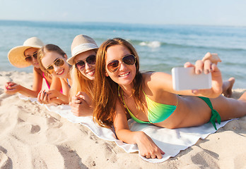 Image showing group of smiling women with smartphone on beach