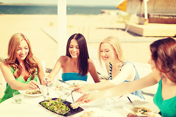 Image showing smiling girls in cafe on the beach