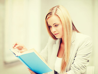 Image showing young woman reading book at school