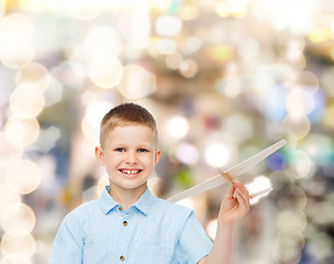 Image showing smiling little boy holding a wooden airplane model