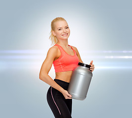 Image showing smiling sporty woman with jar of protein