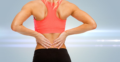 Image showing close up of sporty woman touching her back