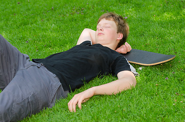 Image showing Teenager with skate resting on grass