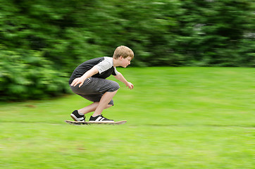 Image showing Young teen guy fast rides a skateboard in park