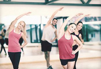 Image showing group of smiling people stretching in the gym