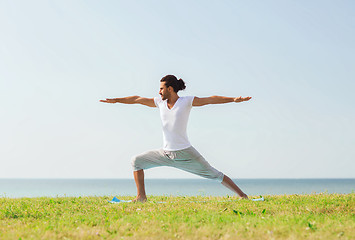 Image showing smiling man making yoga exercises outdoors