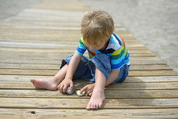 Image showing Boy playing on a wooden walkway on the beach