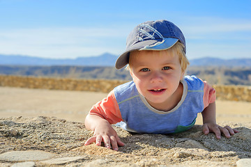 Image showing Small boy laying down on the rock