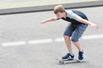 Image showing Young skater teenager guy in motion moving on skateboard