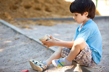 Image showing boy shakes the sand out of the shoe