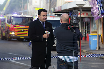 Image showing News correspondent delivers a news bulletin on site of shop blas