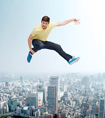 Image showing smiling young man jumping in air