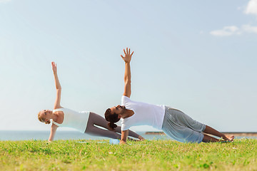 Image showing smiling couple making yoga exercises outdoors