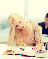 Image showing tired teenage student with tablet pc and books