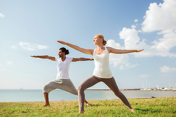 Image showing smiling couple making yoga exercises outdoors